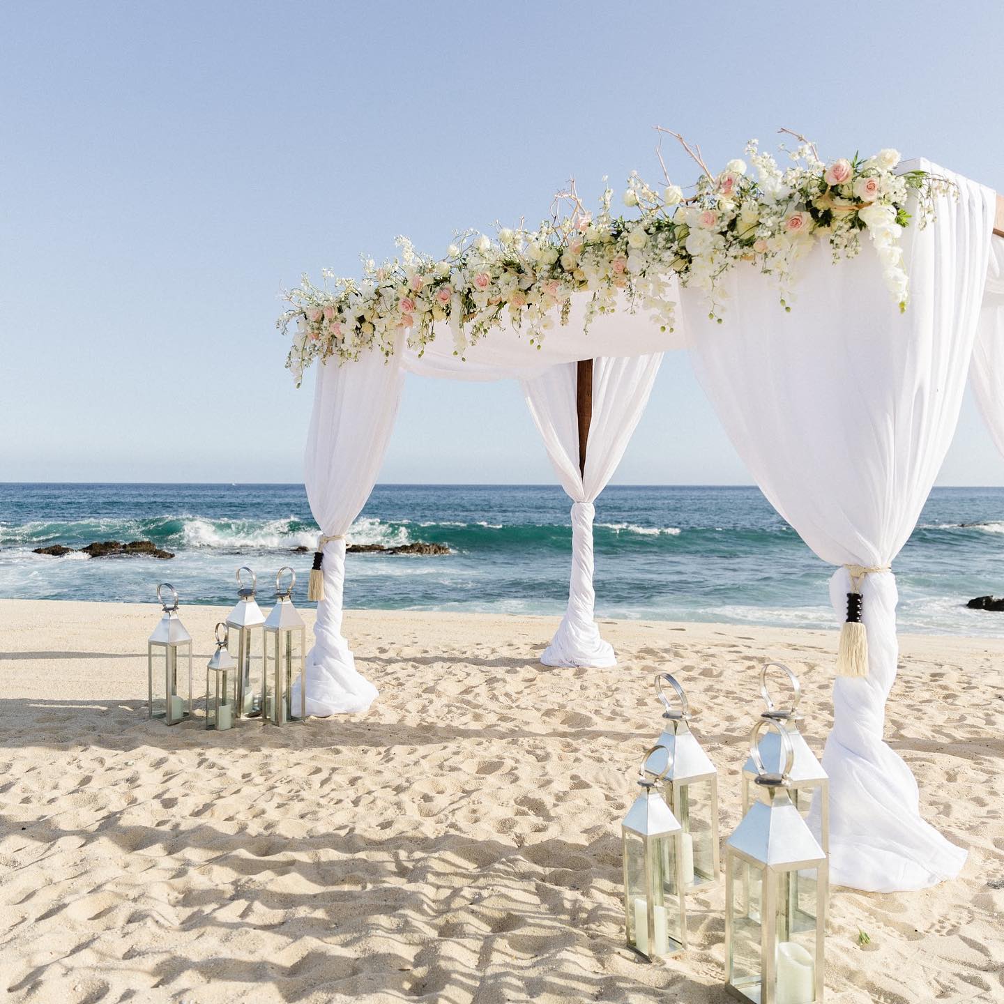 large arch on beach with white flowers and drapery