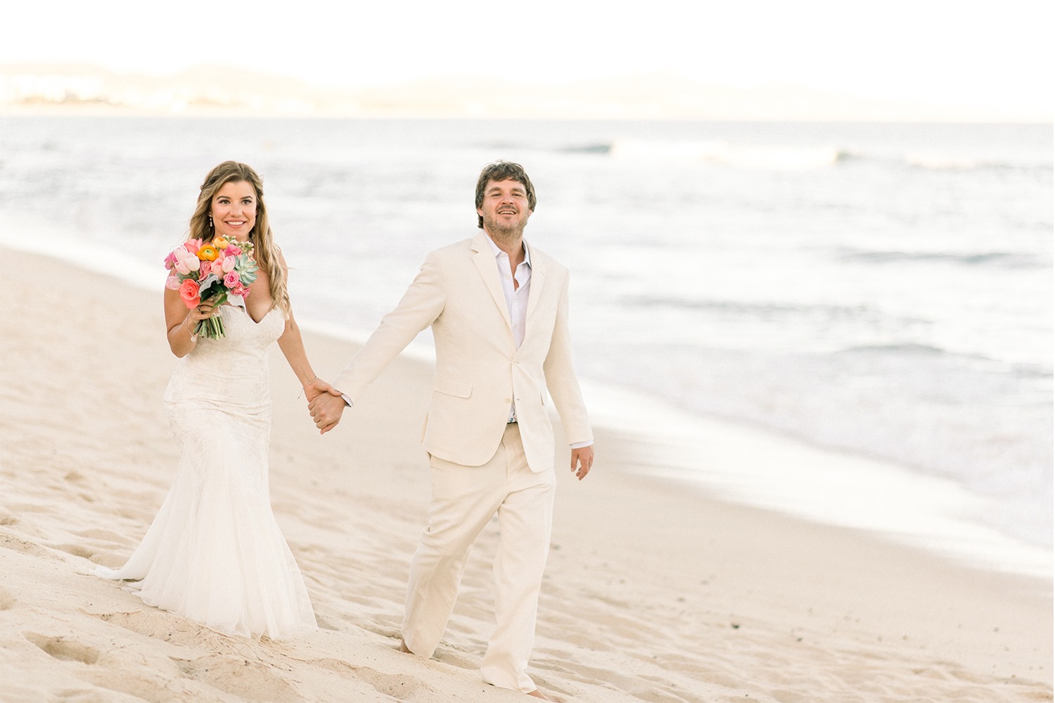 bride and groom walking on cabo beach
