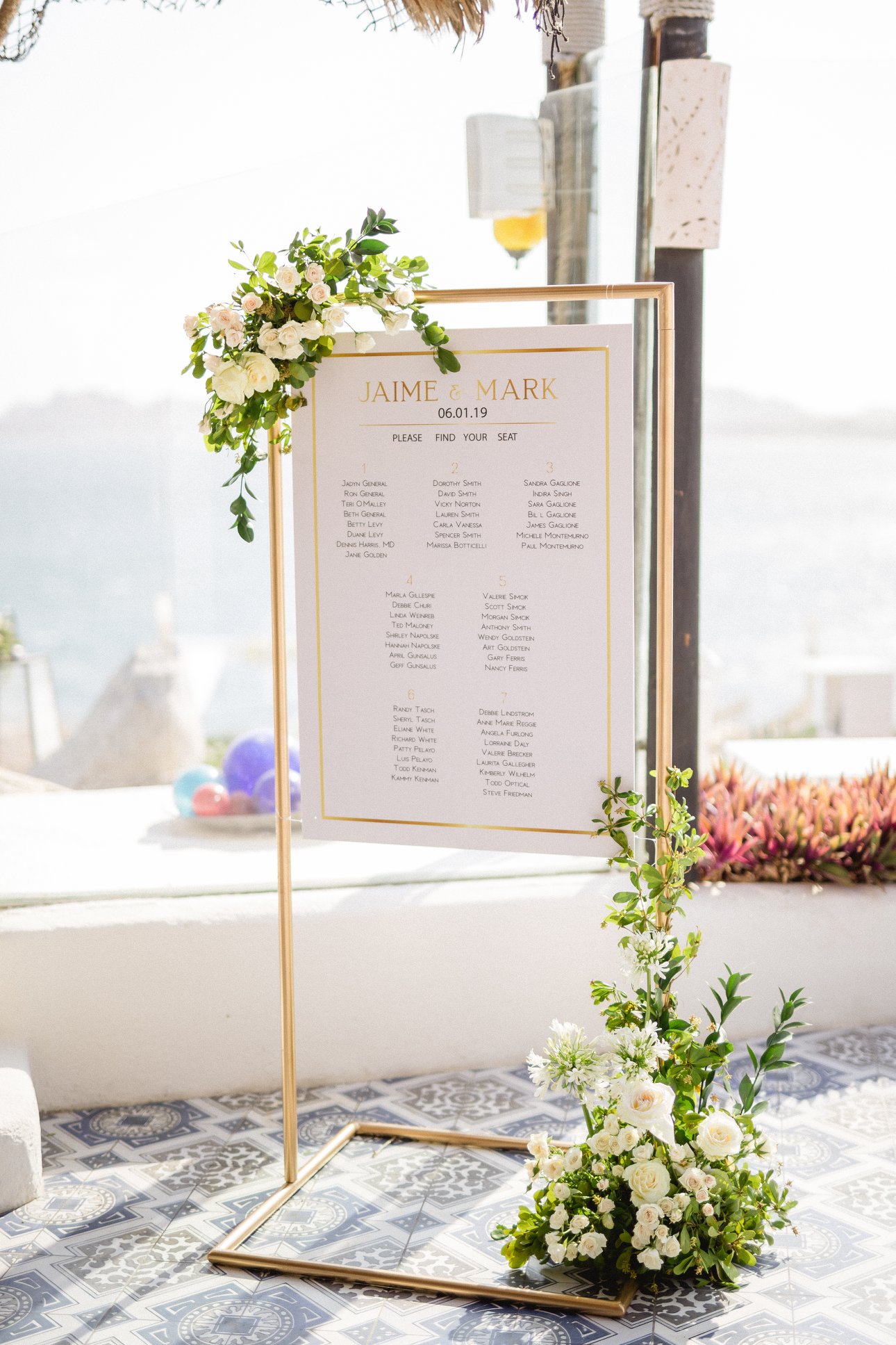gold wedding seating chart with white floral arrangements