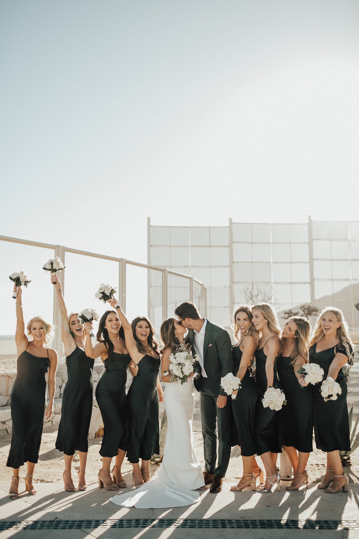 bride and groom kissing while bridesmaids cheer